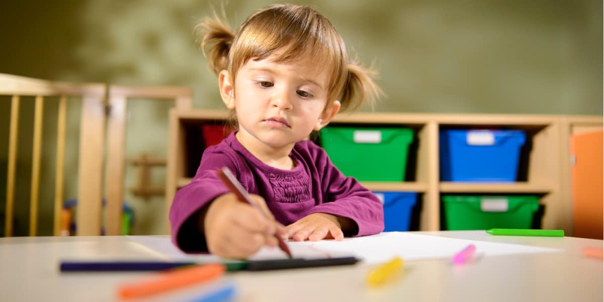 Young girl drawing at a table at daycare