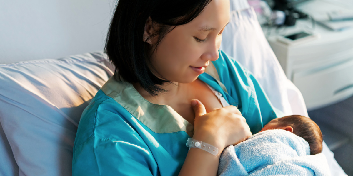 mom breastfeeding baby in hospital bed