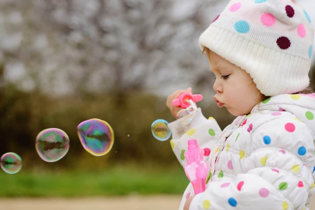 toddler blowing bubbles outside