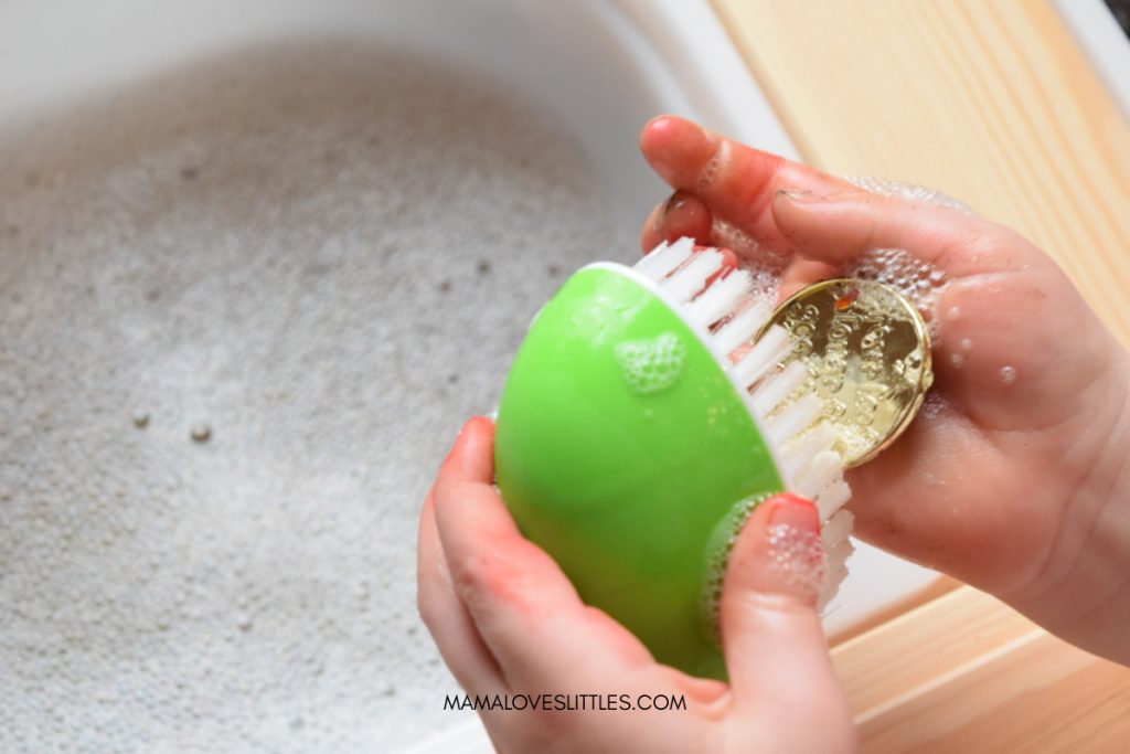 Little girls' hands using scrub brush to clean off piece of leprechaun gold
