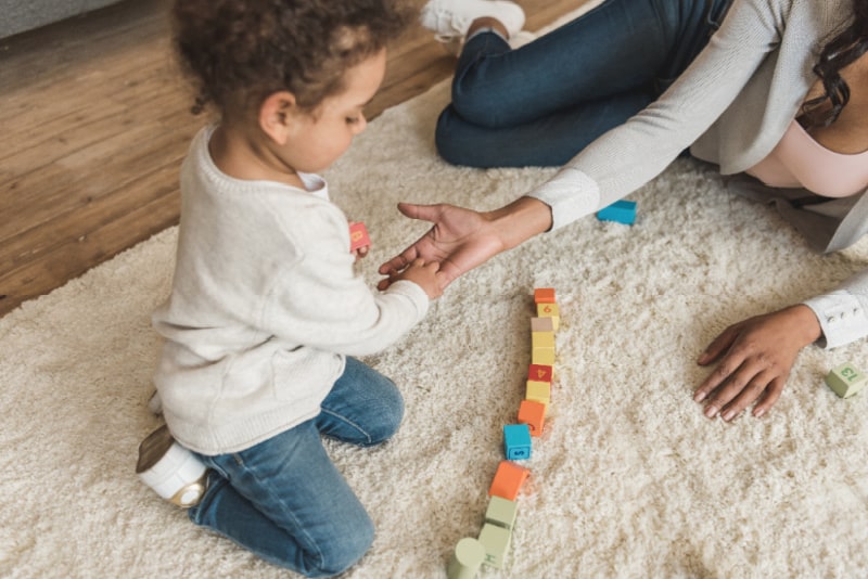 Toddler playing with toy blocks on floor